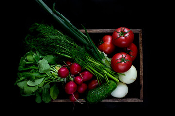 Top view of bunch of colorful vegetables in woodden chest on a black background.Group of fresh tomato, radish, onion, dill, cucumber, black background. Delicious Fresh vegetables from the garden 
