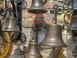 Fototapeta premium Different old metal small bells on the brick wall close-up. 