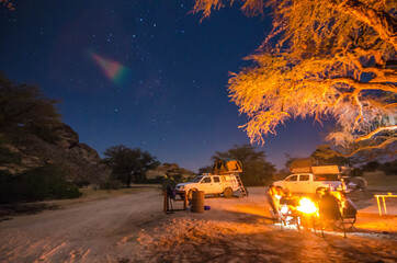 People camping by side the campfire and under the stars next to the mountains of Spitzkoppe-Namibia.