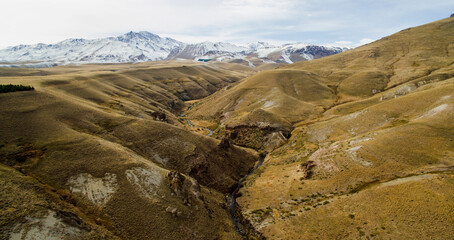 Obraz premium Rural landscape. Steep cliffs and yellow meadow. Aerial view of the river flowing along the golden valley in the mountains. 