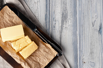 Cut butter on plate with blue towel on kitchen table