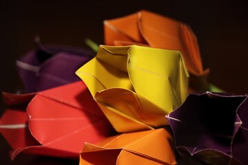 A bouquet of multicolored origami tulip flowers with white ribbon bow on the wood, paper flowers