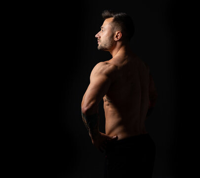 Profile portrait strong man. Male bodybuilder with a naked torso on a black background. Studio photo.