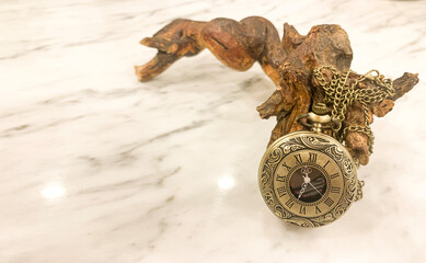 Watch on a chain, bronze metal. Marble table, gloss.