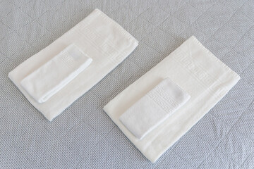 Terry towels on the bed, clean, white, neatly folded. Close-up.