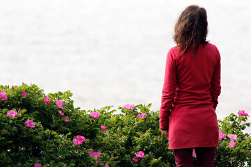 Une femme devant un rosier