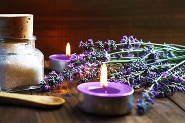 Spa massage setting with lavender flowers, scented aroma candles and cosmetic salt on wooden...