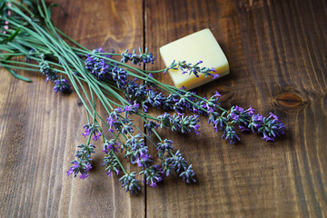 Spa massage setting with lavender flowers, soap on wooden background. SPA salon and beauty concept with warm light.