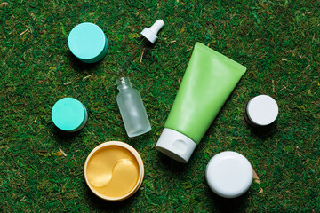 Various cosmetics on a spring background with green grass and petals