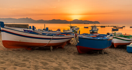 A close up of colourful fishing boats at Aspra Sicily as the sun sets over the Gulf of Palermo on a summer's evening