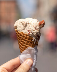 Sweet ice cream in waffle cone in a hand close up. Tiramisu-flavored ice cream.