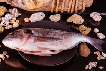pesce sul tagliere con conchiglie e sfondo in legno