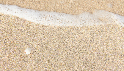 Close-up of golden sand, washed by soft sea waves