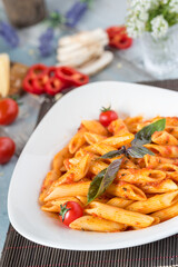 Penne pasta in tomato sauce with chicken, tomatoes decorated with parsley