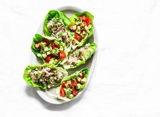 Romaine salad stuffed with tuna, egg, tomato, avocado salad on a light background, top view....