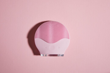 Silicone electric facial cleanser brush for skin care on pink background