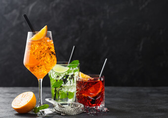 Glasses of spritz,mojito and negroni cocktails with ice cubes and lime and orange slices with mint...