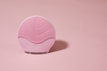 Silicone electric facial cleanser brush for skin care on pink background