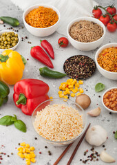 White bowl plates with boiled long grain basmati rice with vegetables and mushrooms on light table background with sticks and paprika pepper with corn,garlic and basil. Healthy vegan food. Top view