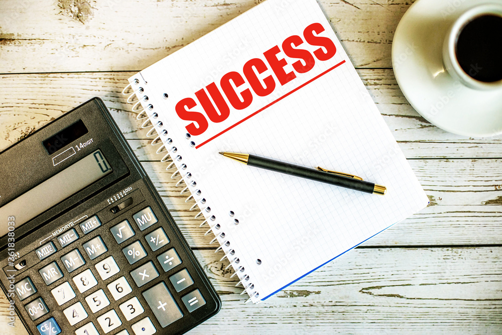 Poster the word success is written in red on a notebook on a light table near a calculator and coffee