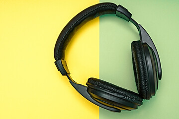 Large, black headphones lie on a colored background. Device for individual listening to music.