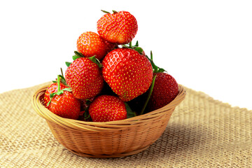 Strawberry. Close-up of sweet ripe strawberries in a basket on burlap isolated on a white background.