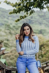 Beautiful model posing for photos on the street. Wearing a blue blouse with white stripes, jeans...