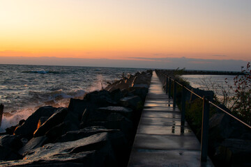 A pier juts out into the water as the sun sets
