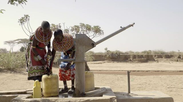 Two women collecting clean water from local borehole. The two women walk around 1.5 km to the borehole from their village. The water containers when full weigh 20kg.