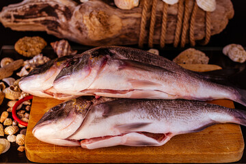 pesce sul tagliere con conchiglie e sfondo in legno