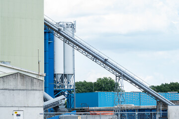 Industrial view of a blue factory buildings, concrete plant with silos and a chute. 