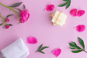 Composition with flowers, petals of peony, natural organic soap and towel. Beauty, skin care concept. Flat lay, top view with place for text on pink background