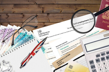 English Tax form sa103 Self-employment from HM revenue and customs lies on table with office items....
