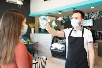 Fototapeta premium Staff Checking Body Temperature Of Customer In Cafe