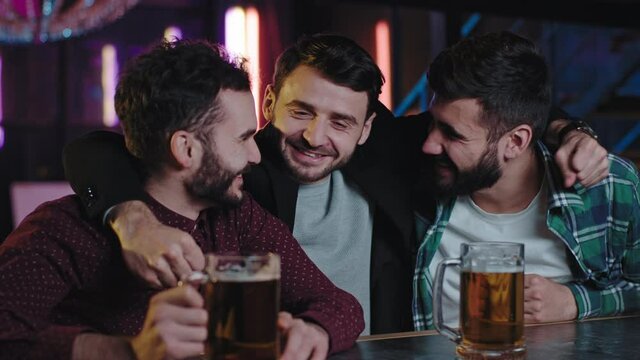 In a pub good looking group of friends three guys with chin drinks some beer and feeling so happy spending a great time. Shot on ARRI Alexa Mini