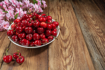 fresh, juicy cherries in a plate on a wooden table close-up, rustic style