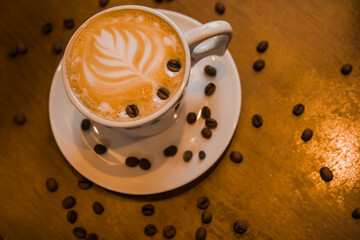 Cup of hot cappuccino on wooden desk background. Breakfast time. Top view. Closed up