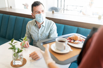 Staff Serving Order To Man In Coffee Shop