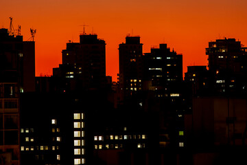 Silhueta de prédios no anoitecer de São Paulo, logo após o pôr-do-sol. Janelas acesas à noite.
