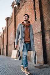 Young man holding shopping bags while walking on the street.