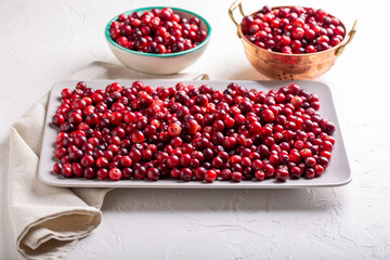 Ripe red cranberry berries on rectangular plate on white background.