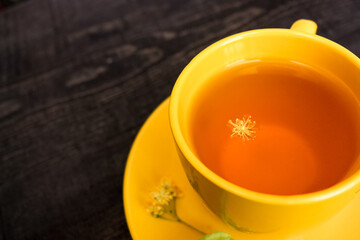 cup with linden tea and flowers on wooden table