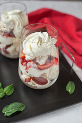 Eton Mess - whipped cream,  meringue, strawberry in glasses on a table. Traditional English dessert.