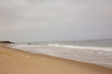 empty beach with white water on grey overcast day