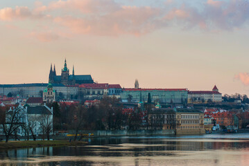 Panorama of Prague, Czech Republic at sunset. View of St. Vitus Cathedral from afar, buildings on the embankment of the Vltava River in the foreground.
