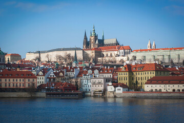 Naklejka na ściany i meble Panorama of Prague, Czech Republic. View of St. Vitus Cathedral from afar, buildings on the embankment of the Vltava River in the foreground.