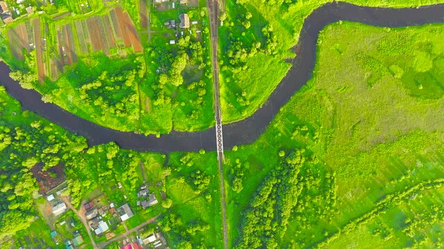 Aerial view landscape of winding small river among the small town, stream in green field, top view meadow