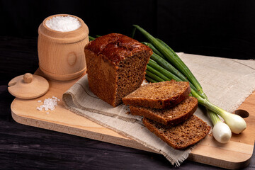 Fototapeta na wymiar black bread on a linen napkin with green onions, eggs and salt in a wooden jar