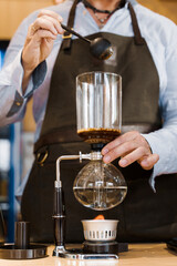 Fototapeta na wymiar Coffee brewing by Syphon device. Close up syphon is heating by fire. Brewing photo on the fire. Alternative method of coffee making. Vertical photo for advert in social networks