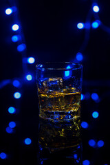 Glass of whiskey on the rocks with some ice on the table.